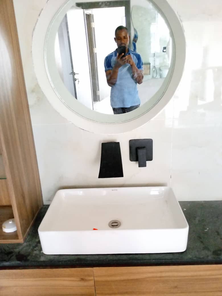 Round mirror above a rectangular vessel basin on granite counter